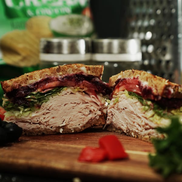 A turkey sandwich from The Great Wazu, cut in half, revealing layers of meat, lettuce, and tomato.